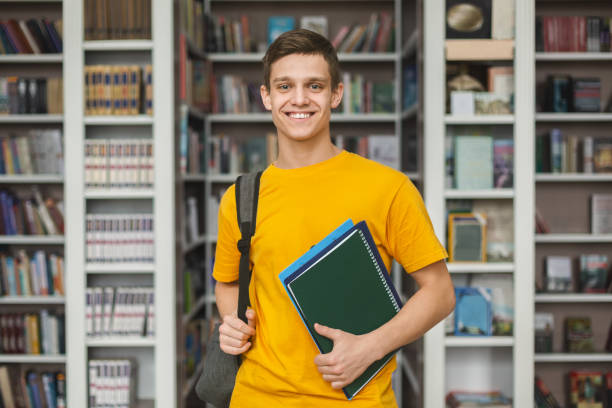 istock Handsome young guy standing in library, bookshelves background 1172140369