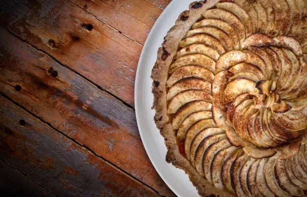 Traditional french apple tart over brown planks background