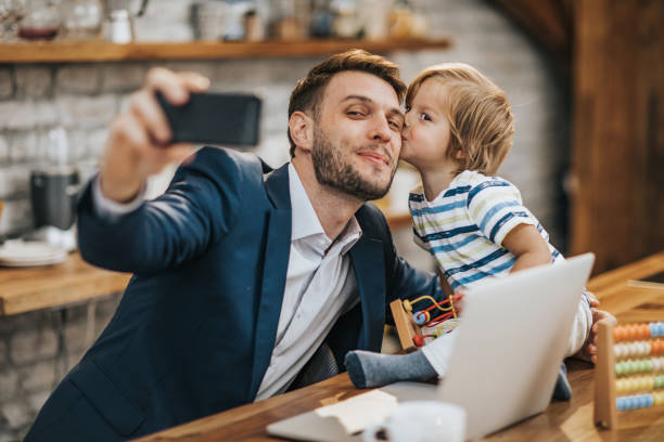 istock Affectionate businessman and his son taking a selfie with cell phone at home. 1172143562