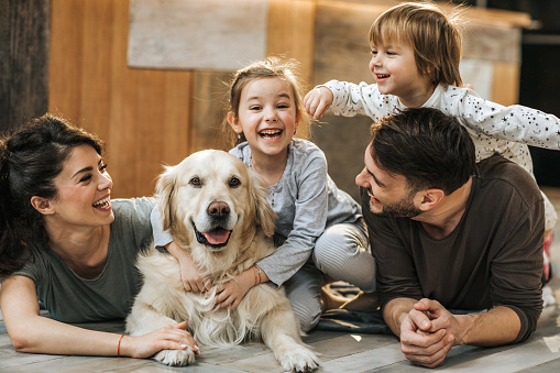 Happy family relaxing on the floor with their dog at home.
