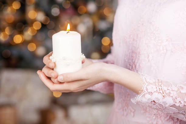 Burning candle in the hands of a girl. Christmas candle. Christmas decor. Child's hands holding beautiful candle with fire stock photo