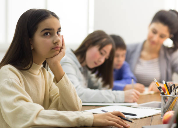 istock Boring lesson. Upset school girl sitting at lesson 1172146923