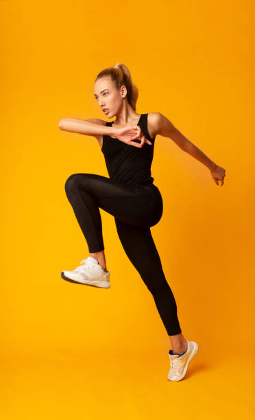 istock Woman Jumping Exercising On Yellow Background In Studio 1172147279