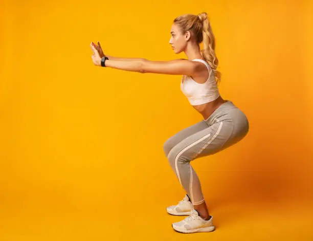 Photo of Young Lady Doing Deep Squat Exercise, Studio Shot, Side View