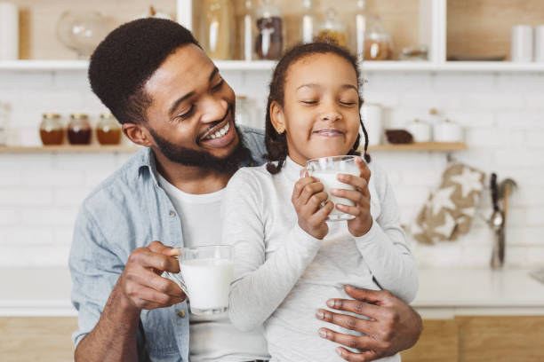 african father encouraging daughter to drink milk - glasses child cute offspring imagens e fotografias de stock