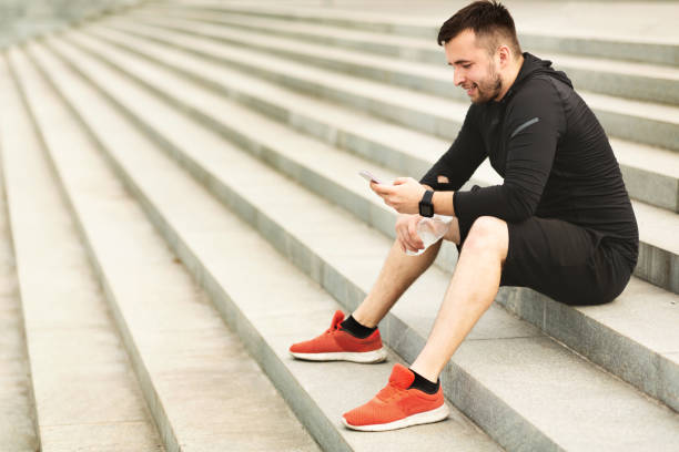 istock Man texting on cellphone while sitting on stairs after jogging 1172150181