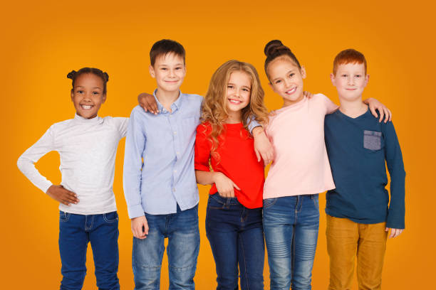 istock Happy kids hugging against orange studio background 1172150266