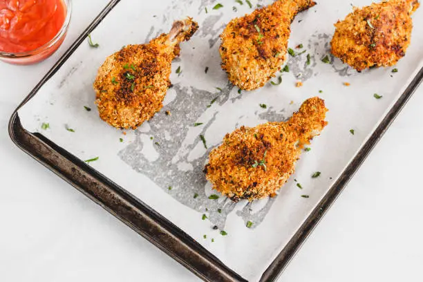 Crispy and Crunchy Breaded Oven Fried Chicken Drumsticks on a Baking Sheet Pan on with Tomato Ketchup.