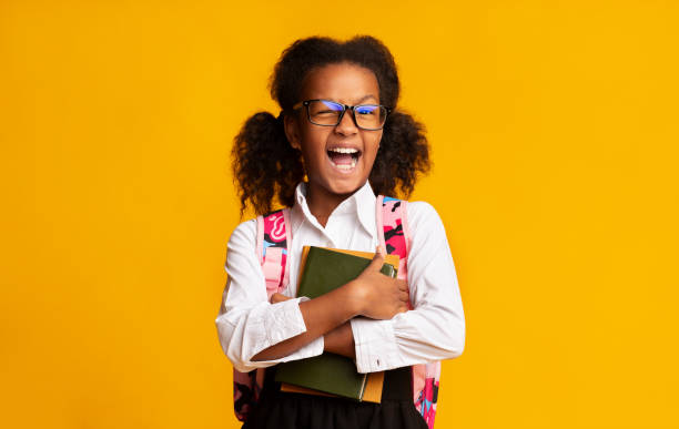 istock Afro Elementary Student Girl Winking At Camera Over Yellow Background 1172152095