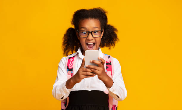 istock Excited Schoolgirl Using Smartphone On Yellow Background In Studio 1172152333