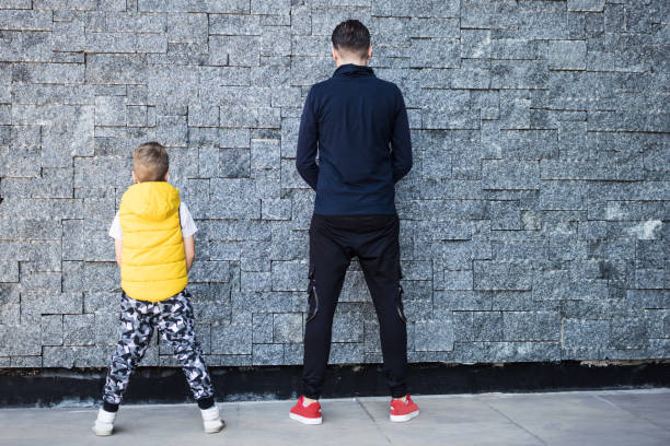 istock Rear view of father and son against the wall. 1172152421