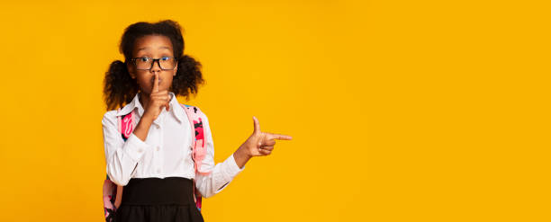 istock Afro Schoolgirl Putting Finger To Lips Pointing At Copyspace 1172152442