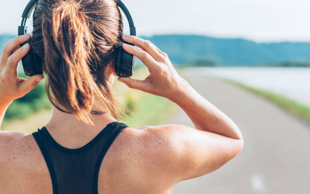 fermez-vous vers le haut de l'image d'adolescent ajustant le casque sans fil avant de commencer le jogging et écoutant la musique - beautiful caucasian teenager running photos et images de collection