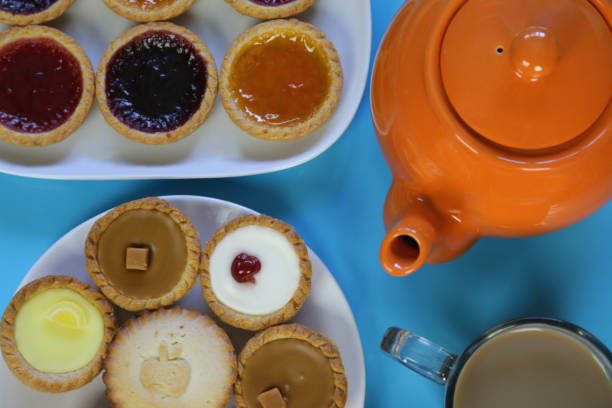 imagen del picnic buffet de té de la tarde de pasteles de cupcakes, tartas de pastel de cereza, receta de magdalenas heladas de chocolate con glaseado y espolvoreadas de mantequilla, tartas de mermelada de fresa con tetera de naranja en la fiesta del jard - fondant fancies fotografías e imágenes de stock