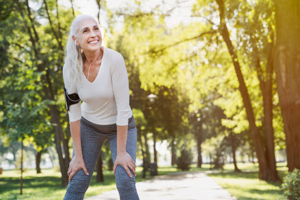 retrato de mujer madura atlética descansando después de correr al aire libre en el parque - senior adult relaxation exercise healthy lifestyle exercising fotografías e imágenes de stock