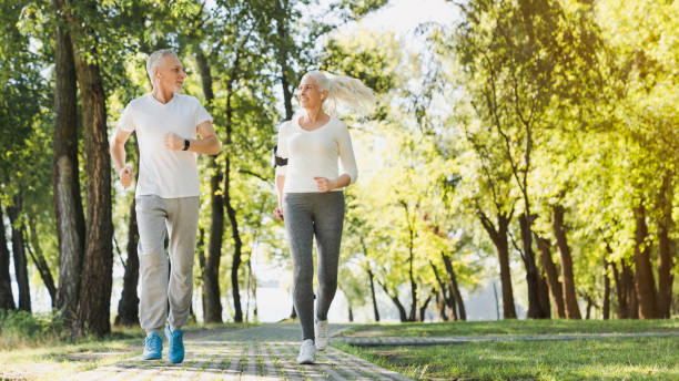 comprimento cheio de pares maduros saudáveis que movimentam-se no parque no amanhecer - couple stretching running jogging - fotografias e filmes do acervo