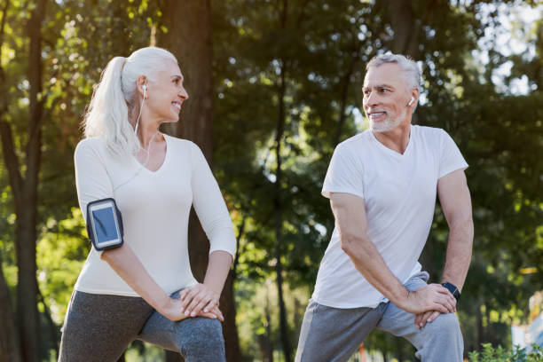 istock Low angle view of smiling senior couple doing warm up exercises while standing in park outdoors and looking on each other 1172161143
