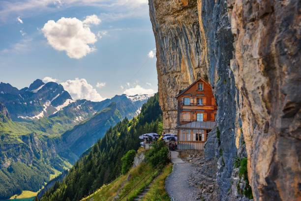 swiss alps and a restaurant under a cliff on mountain ebenalp in switzerland - ascher imagens e fotografias de stock