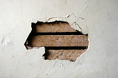 istock Hole in Plaster Wall - Exposed Wood Paneling 117217184
