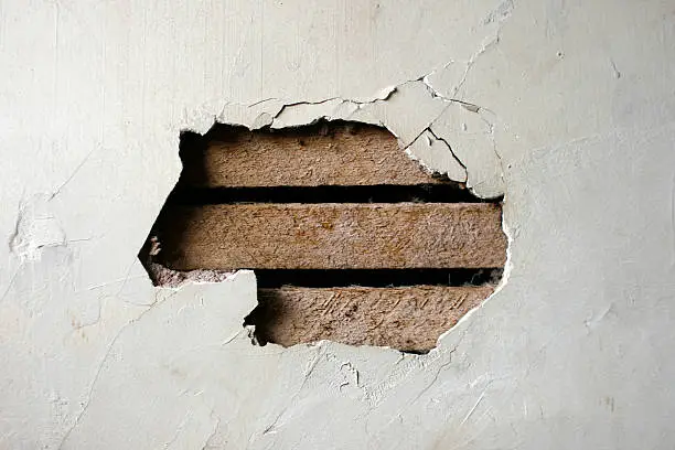 Closeup of a hole in a plaster wall.