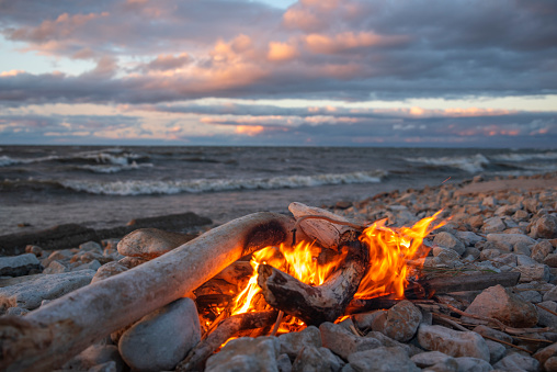 A fire burns near the sea at sunset.