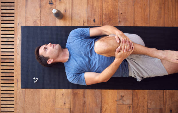 istock Overhead View Of Man Lying On Exercise Mat On Wooden Floor 1172176139