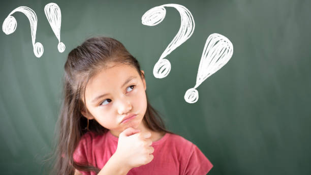istock little girl standing against chalkboard with question mark 1172177195