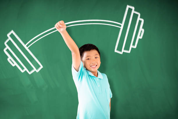 istock happy asian boy standing against chalkboard and  strong winner concept 1172177406