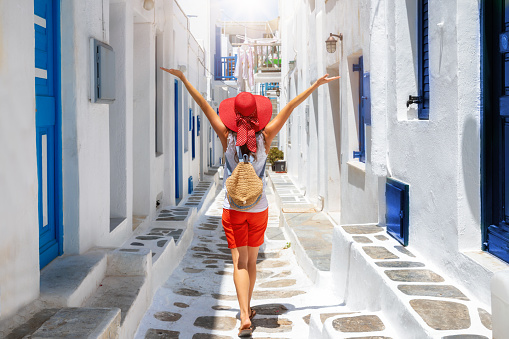 Woman walks through the white and blue streets of the Cyclades islands of Greece