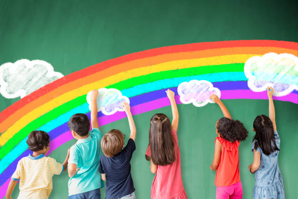 school children drawing rainbow on the chalkboard