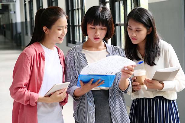 istock Young woman students discussing at corridor 1172182584