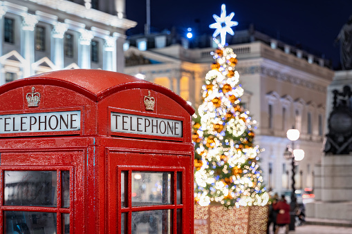 Christmas time in London: a red telephone booth in front of an illuminated Christmas Tree in Central London, UK, during night time