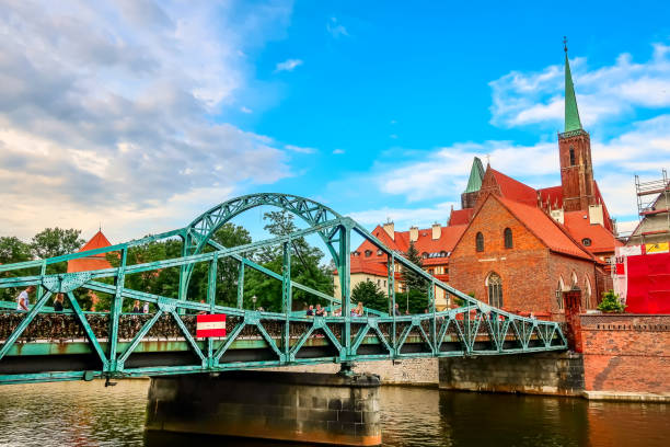 Wroclaw, Poland - June 21, 2019: Tumski Bridge, leading to the Ostrow Tumski district. Belfries of the Church of the Holy Cross and the Cathedral of St. John the Baptist
