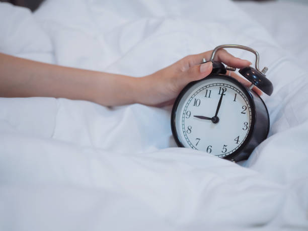 istock hand holding alarm clock on the bed 1172188202