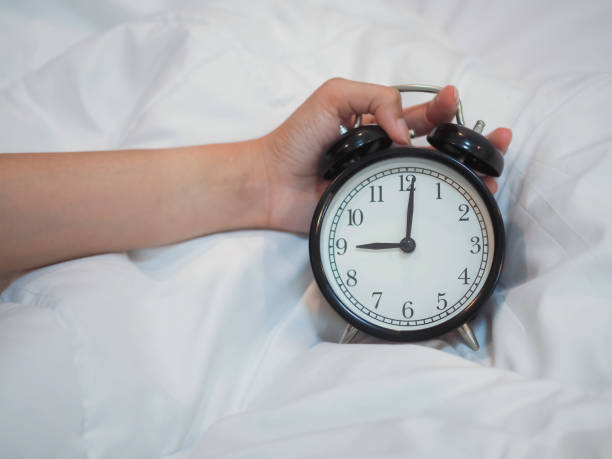 istock hand holding alarm clock on the bed 1172188232