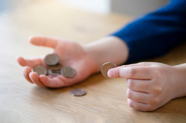 istock Kid hand holding pound coins on wooden table, Kid learning  counting and how different about money coins 1172188588
