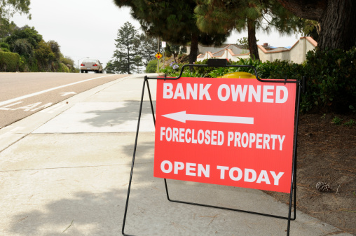 Image of a directional sign pointing to a foreclosed home in a suburban neighborhood in Southern California.