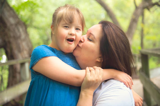 un portrait de trisomie 21 enfant fille à l'extérieur avec sa mère - child cheerful little girls down syndrome photos et images de collection