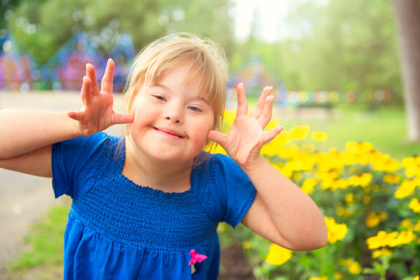 un retrato de trisomie 21 niña fuera divirtiéndose en un parque dando un poco sombrío - friendship park flower outdoors fotografías e imágenes de stock