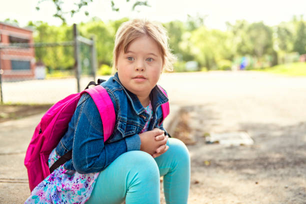 un portrait de trisomie 21 enfant fille à l'extérieur sur une cour de récréation d'école - child cheerful little girls down syndrome photos et images de collection