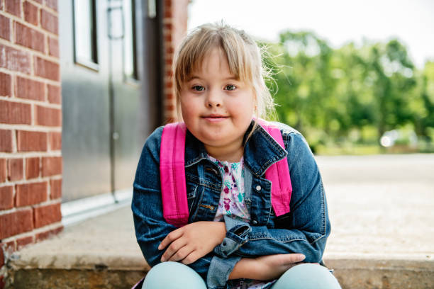 un portrait de trisomie 21 enfant fille à l'extérieur sur une cour de récréation d'école - child cheerful little girls down syndrome photos et images de collection