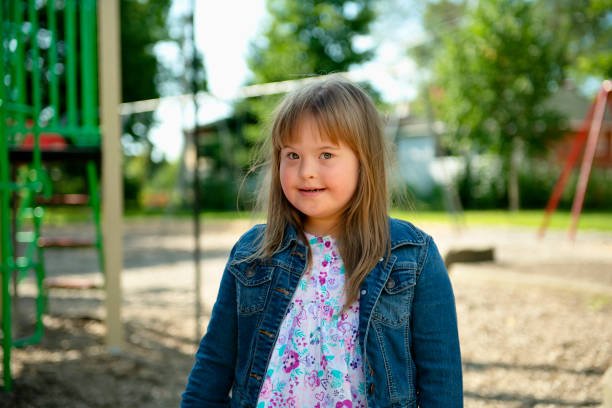un portrait de trisomie 21 enfant fille à l'extérieur ayant l'amusement sur un stationnement - child cheerful little girls down syndrome photos et images de collection