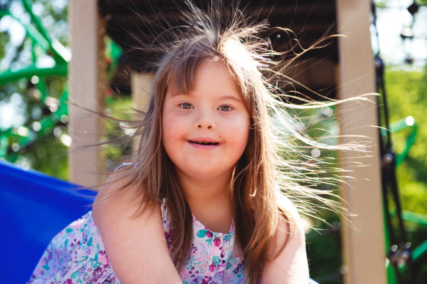 un portrait de trisomie 21 enfant fille à l'extérieur ayant l'amusement sur un stationnement - child cheerful little girls down syndrome photos et images de collection