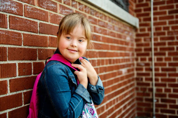 un portrait de trisomie 21 enfant fille à l'extérieur sur une cour de récréation d'école - child cheerful little girls down syndrome photos et images de collection