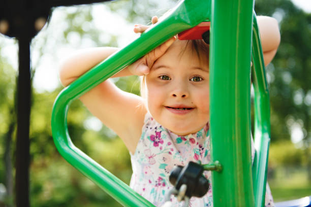 un portrait de trisomie 21 enfant fille à l'extérieur ayant l'amusement sur un stationnement - child cheerful little girls down syndrome photos et images de collection