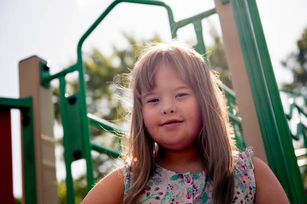 un portrait de trisomie 21 enfant fille à l'extérieur ayant l'amusement sur un stationnement - child cheerful little girls down syndrome photos et images de collection