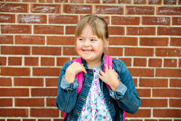 un portrait de trisomie 21 enfant fille à l'extérieur sur une cour de récréation d'école - child cheerful little girls down syndrome photos et images de collection