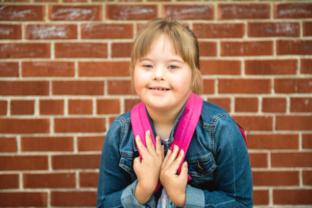 un portrait de trisomie 21 enfant fille à l'extérieur sur une cour de récréation d'école - child cheerful little girls down syndrome photos et images de collection