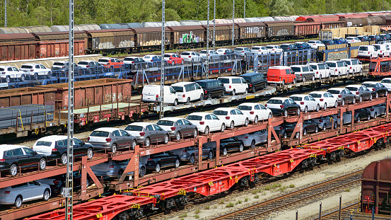 Munich, Germany - July 10, 2019: lots of new cars loaded on railway autorack wagons and ready for shipment from factories to automotive distributors