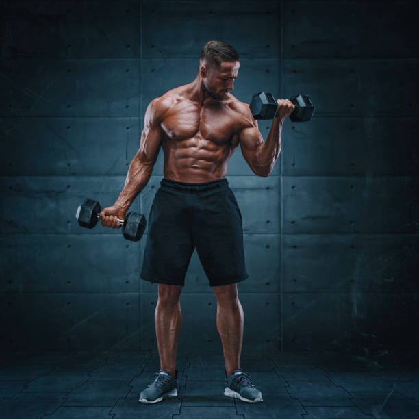 istock Muscular Men Exercise With Weights. He is performing bicep curls with dumbbels 1172198547